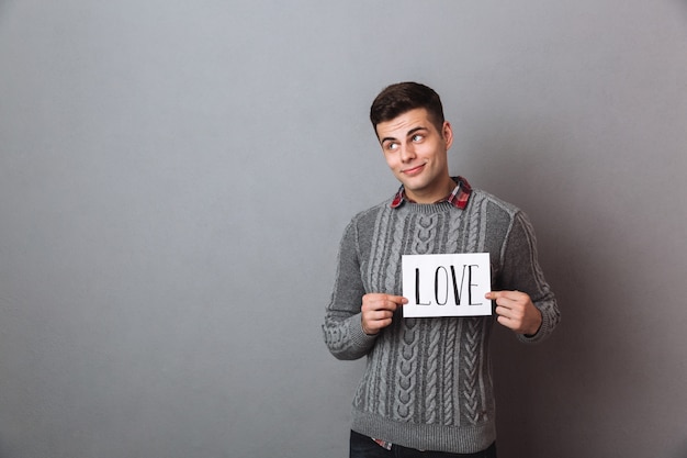 Young man standing isolated over grey wall