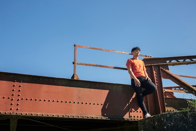 Free photo young man standing on metallic bridge