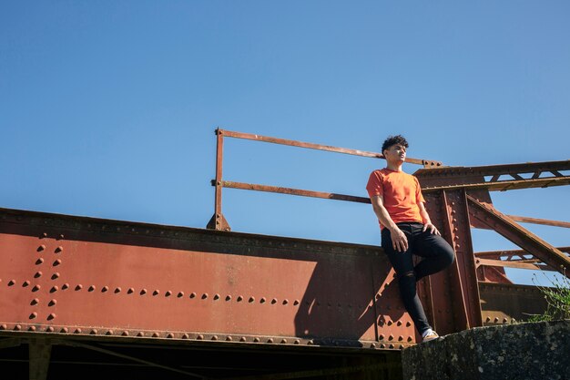 金属製の橋の上に立っている若い男