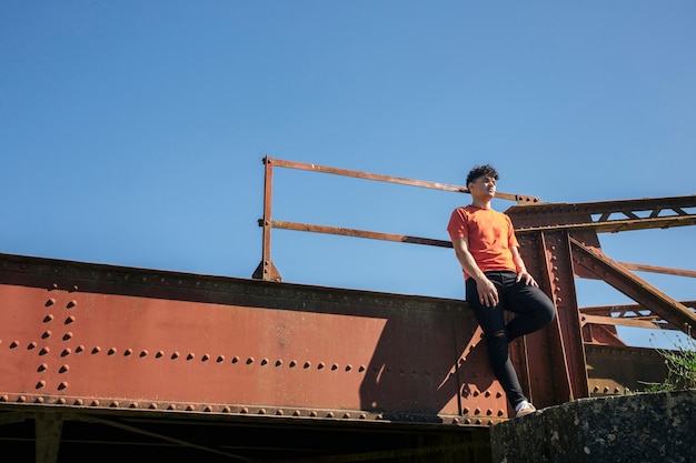Молодой человек, стоящий на металлическом мосту