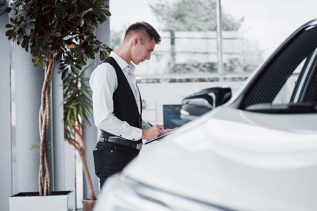 車に対してショールームに立っている若い男