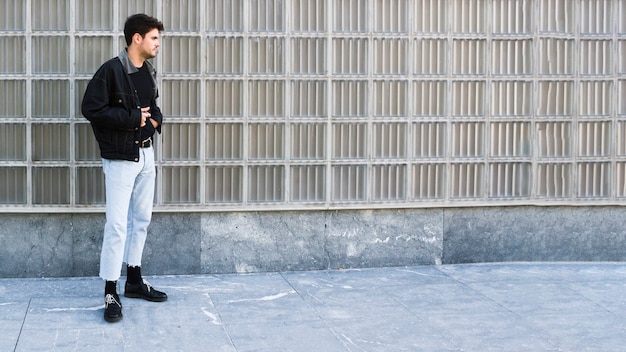 Young man standing sideways on street 