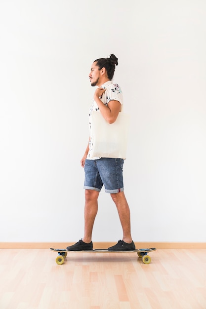 Young man standing on skatingboard over the hardwood floor