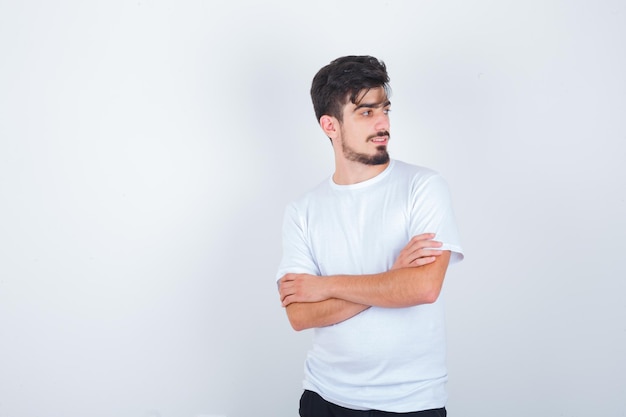 Young man standing with crossed arms in t-shirt and looking charming