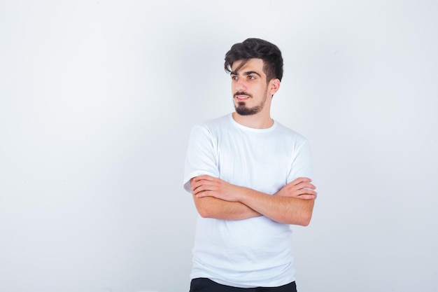 Free photo young man standing with crossed arms in t-shirt and looking confident