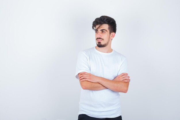 Young man standing with crossed arms in t-shirt and looking confident