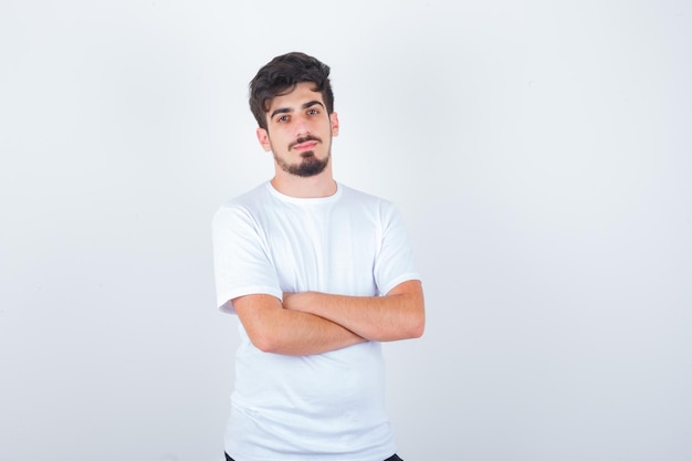 Young man standing with crossed arms in t-shirt and looking confident