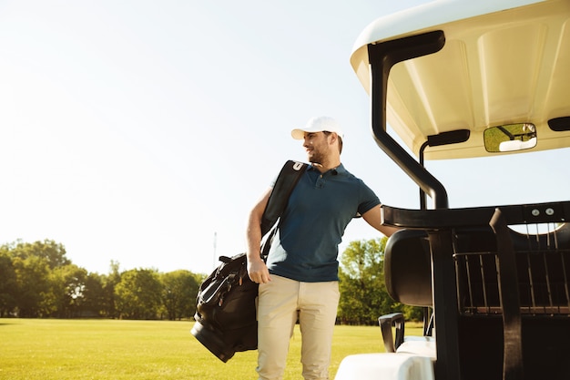 Молодой человек стоял с сумкой для гольфа