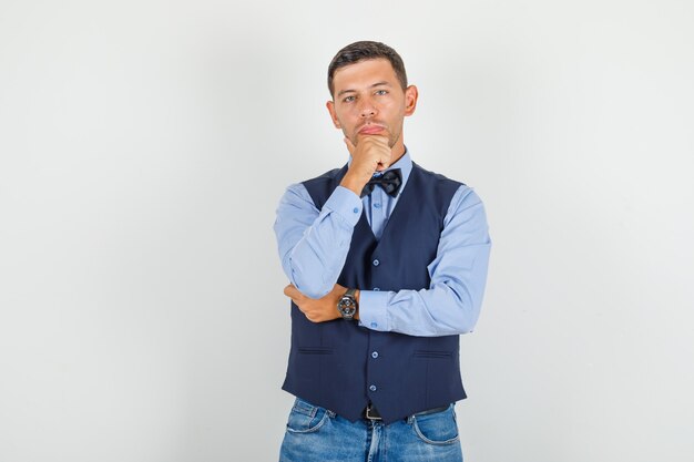 Young man standing with hand on chin in suit