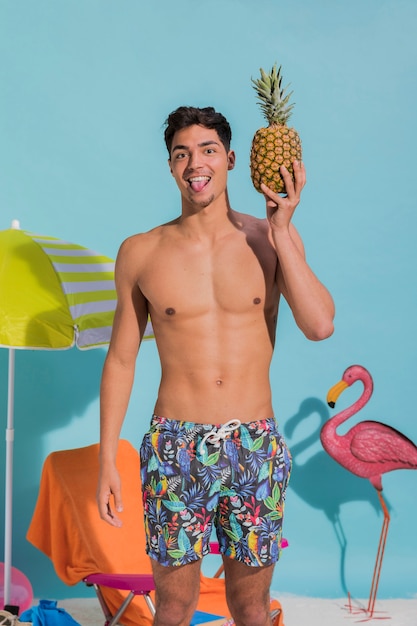 Young man sticking tongue out and holding pineapple
