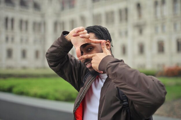 young man in the street creates a frame around his eye with his hands