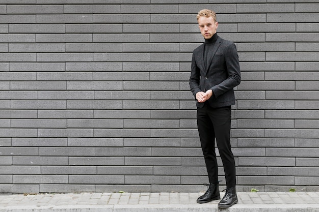 Young man on the street near a gray wall