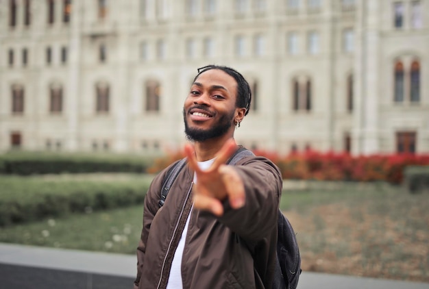 young man in the street with backpack with victory gesture