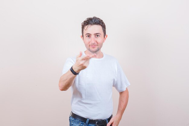 Young man stretching hand and fingers in white t-shirt, jeans and looking confident