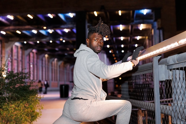 Free photo young man stretching at night in the city