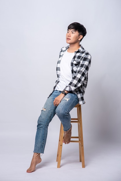 A young man in a striped shirt is sitting on a high chair.