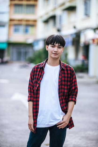 A young man in a striped shirt is standing on the street.