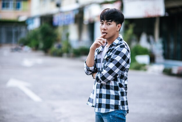 A young man in a striped shirt is standing on the street.