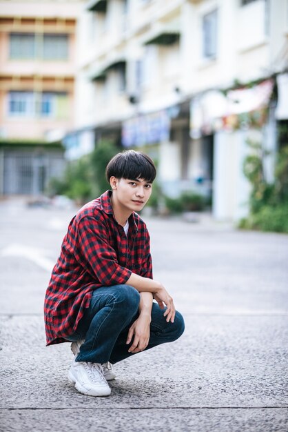 A young man in a striped shirt sitting on the street