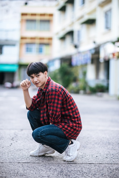 A young man in a striped shirt sitting on the street