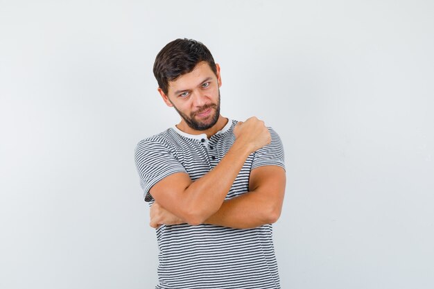 Young man in striped t-shirt showing clenched fist and looking confident , front view.