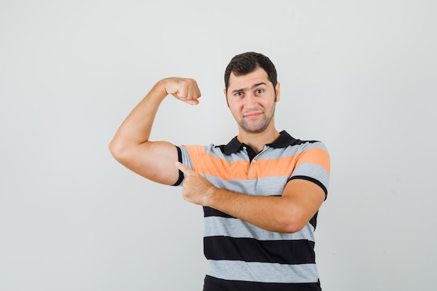 Free photo young man in stripled t-shirt showing his arm muscles and looking powerful