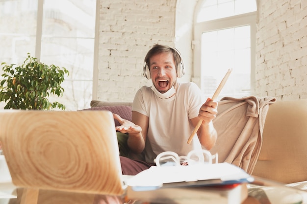 Young man studying at home during online courses for musician, drummer, producer.