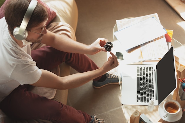 Young man studying at home during online courses for photographer, studio assistant.