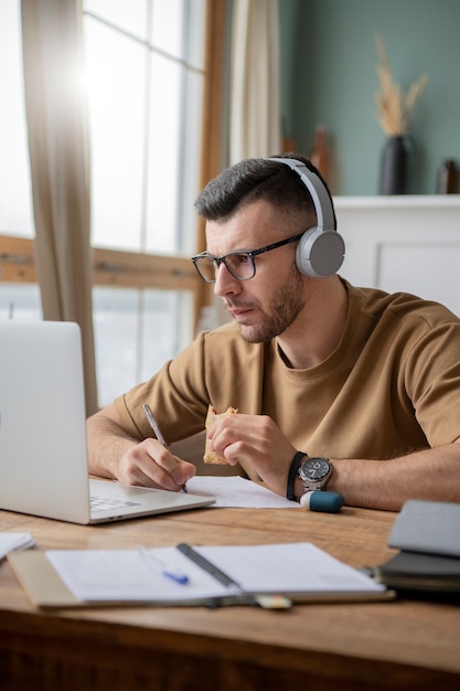 Foto gratuita giovane che studia in una biblioteca usando un computer portatile