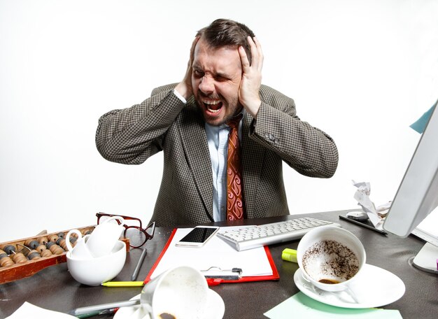 Young man suffering from the colleagues' talks in the office