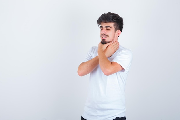 Young man suffering from sore throat in white t-shirt and looking sick