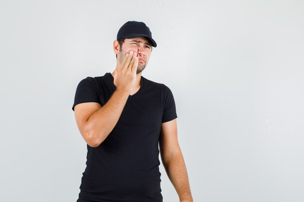 Young man suffering from toothache in black t-shirt