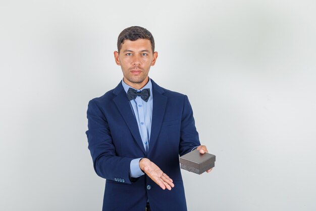 Young man in suit holding watch box and looking glad 