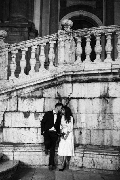 Young man in suit kissing woman leaning on wall