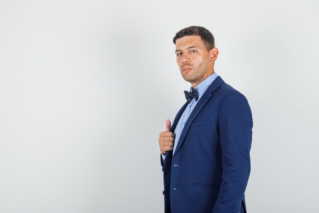 Young man in suit showing thumb up and looking confident .