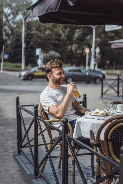 テラスの夏のカフェで若い男が朝食を食べます