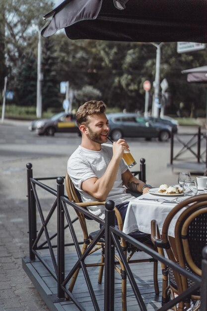 테라스에 있는 여름 카페에서 젊은 남자가 아침을 먹는다