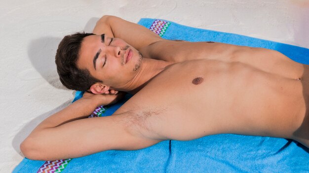 Young man sunbathing on beach