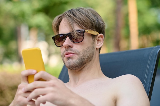 A young man in sunglasses with a smartphone in hands
