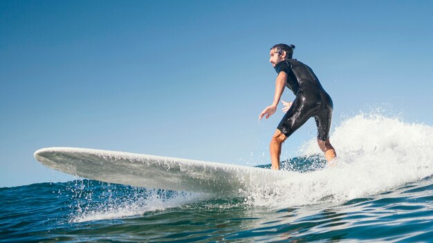 若い男は海の波をサーフィンします