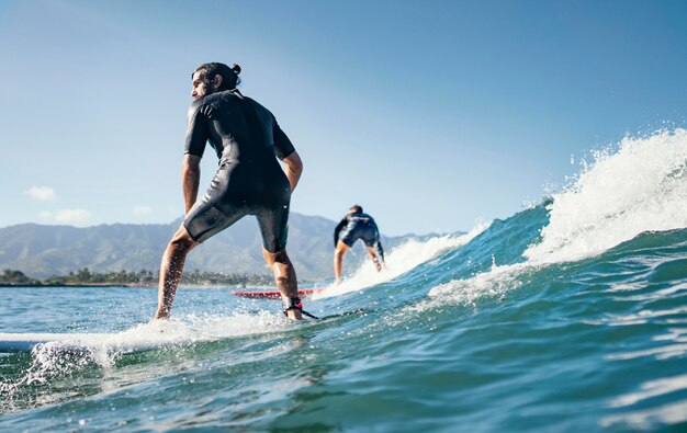 若い男は海の波をサーフィンします