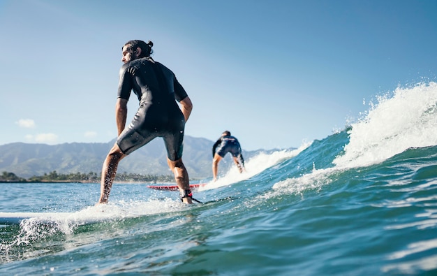 若い男は海の波をサーフィンします