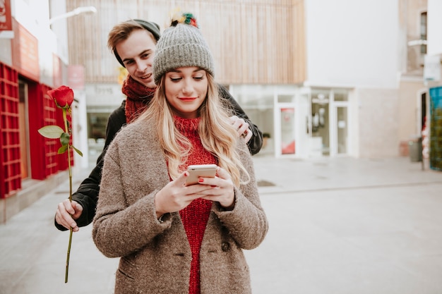 Young man surprising girl with flower