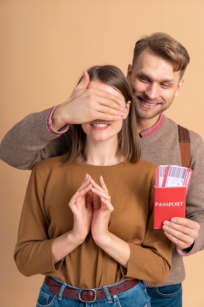 young man surprising girlfriend with passport and plane tickets for traveling