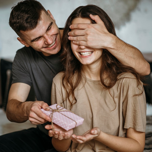 Young man surprising girlfriend with present