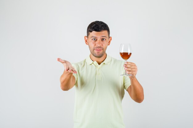 Young man in t-shirt holding glass of drink , front view.