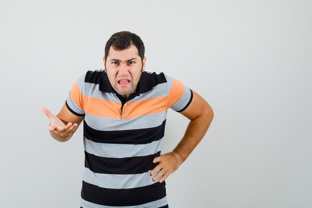 積極的に手を上げて緊張しているTシャツの若い男