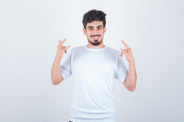 Young man in t-shirt showing i love you gesture and looking joyful