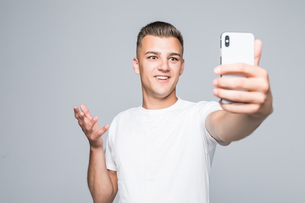Young man take selfie isolated on gray