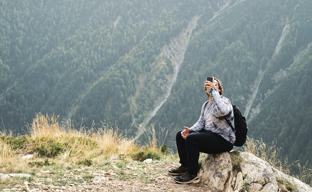 Foto gratuita il giovane scatta foto sul suo telefono durante un'escursione in montagna e attività ricreative attive